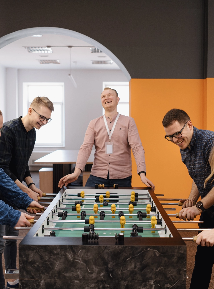 young-office-workers-playing-table-soccer@2x